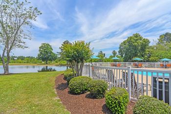 a deck overlooking a lake with tables and umbrellasat The Pointe Apartment Homes, Gautier, MS